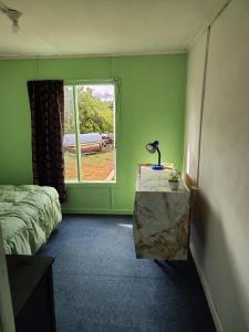 a green room with a bed and a window at Magic Hause Patagonia in Puerto Natales