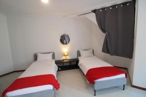 two beds with red and white blankets in a room at Casas da Biquinha in Sintra