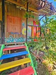a wooden house with colorful benches in front of it at Hakuna Matata Ecolodge in El Valle