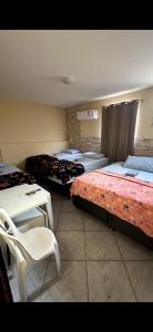 a room with three beds and a table and a chair at Pousada caminho das praias jp in João Pessoa