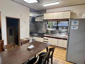 a kitchen with a table and chairs and a refrigerator at さくらの宿Traditional Japanese house with cherry blossoms in Hasunuma