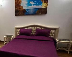 a bedroom with a purple bed with a painting on the wall at CENTRO Guest House in Alytus