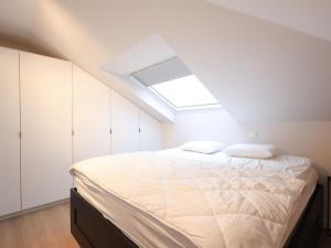1 dormitorio blanco con 1 cama con tragaluz en Plaza Z22 located near the beach, en Oostduinkerke
