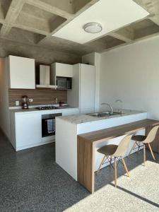 a kitchen with white cabinets and a sink and two chairs at Brand new apt San Bernardino Caracas in Caracas