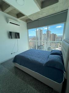 a bedroom with a blue bed and a large window at Brand new apt San Bernardino Caracas in Caracas