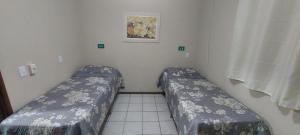 a small room with two beds in a room at Pousada Palmeira in Viracopos