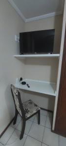 a desk with a chair and a television on a wall at Pousada Palmeira in Viracopos