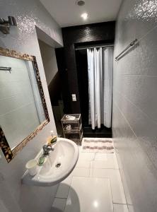 La salle de bains est pourvue d'un lavabo blanc et d'une douche. dans l'établissement CENTRO Guest House, à Alytus