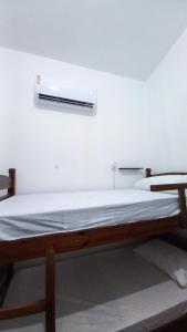 a bed in a room with a white wall at Yolo Hostel in João Pessoa