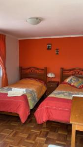 Duas camas num quarto com paredes cor de laranja em B&B SANTA CECILIA em Sucre
