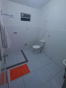 a white bathroom with a toilet and a window at Yolo Hostel in João Pessoa