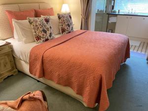 ein Schlafzimmer mit einem großen Bett mit einer orangefarbenen Decke in der Unterkunft Rosewood Guesthouse in Margaret River Town