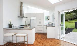 a kitchen with white cabinets and a counter with stools at Ranfurly holiday home in Auckland