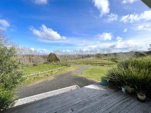 una terraza de madera con vistas a un campo en Ranfurly holiday home, en Auckland