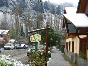 un letrero para un restaurante en una calle con una montaña cubierta de nieve en Hosteria Cumelen en San Martín de los Andes