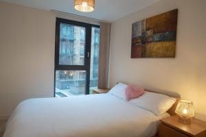 a bedroom with a white bed and a window at Discover Comfort and Style - Your Elegant Stay Offers a 2-Bedroom Haven with Free Parking and Coffee! in Birmingham