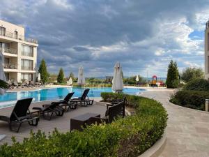 a pool with chairs and umbrellas next to a building at Diamond Beach Apartment 2 Room in Burgas City +4 photos