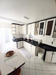 uma grande cozinha com armários brancos e uma mesa em Apto 2 Quartos, pertíssimo da Beira-Mar e Ponte HL em Florianópolis