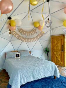 a bedroom with a tent with a bed and balloons at Juncos Glamping in Fúquene