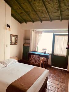 a bedroom with a bed and a desk next to a window at Hotel Posada de San Agustin in Tunja