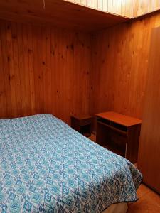 1 dormitorio con 1 cama y pared de madera en Cabaña Interior con entrada independiente, en Osorno