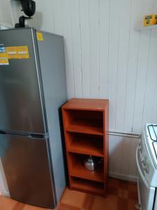 a small kitchen with a refrigerator and a wooden shelf at Cabaña Interior con entrada independiente in Osorno