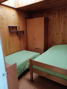 two beds in a room with wooden walls at Cabaña Interior con entrada independiente in Osorno