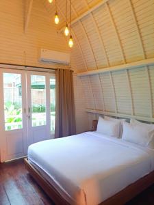 ein Schlafzimmer mit einem großen weißen Bett und einer Tür in der Unterkunft Wong Village in Tumbak Bayuh