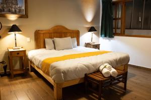 a bedroom with a large bed with two lamps and two tables at Hotel Casa del Fraile in Morelia