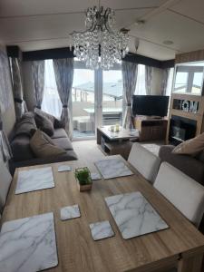 a living room with a table and a chandelier at Swn y Mor (Glamorgan 23) in New Quay