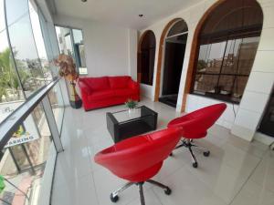 a living room with red chairs and a red couch at CasaHotel Jockey Plaza Mall in Lima