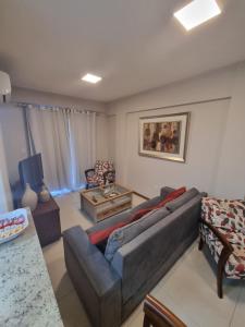 uma sala de estar com um sofá e uma mesa em Apto luxo de 2 quartos, 3 banheiros Praia do forte em Cabo Frio