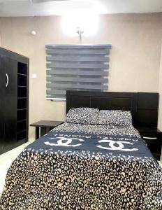 a bedroom with a bed with a black and white comforter at DIVINE VILLA AND RESORTS HOTEL GUEST House 15 mins Near Michael Okpara University Sam Mbakwe Airport in Umuhu