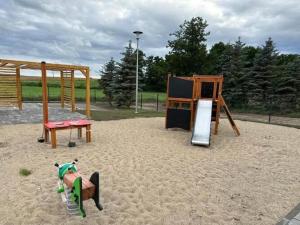 un parque infantil con columpios en la arena en Holiday homes with sauna and jacuzzi in Trz sacz, en Trzęsacz