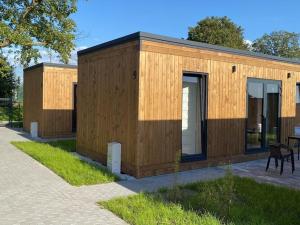 un pequeño edificio de madera al lado de una acera en Holiday homes with sauna and jacuzzi in Trz sacz, en Trzęsacz