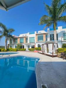 a swimming pool in front of a building with palm trees at Hermosa casa con vista al lago de Tequesquitengo !! in Tequesquitengo