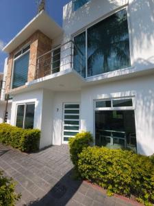 a white house with a palm tree on the balcony at Hermosa casa con vista al lago de Tequesquitengo !! in Tequesquitengo