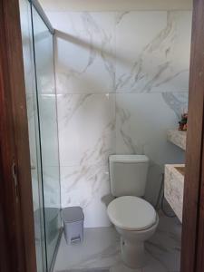uma casa de banho branca com um WC e uma cabina de duche em vidro. em Suite em ótima localização em Santarém