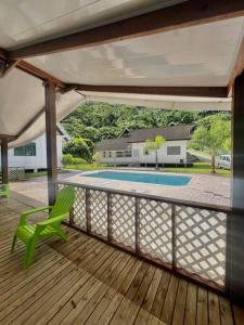 a deck with a green chair and a swimming pool at Taina - dans la baie de Faaroa in Taputapuapea
