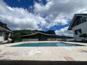 a swimming pool in front of a house at Taina - dans la baie de Faaroa in Taputapuapea