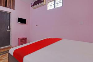 um quarto branco com uma cama com um cobertor vermelho em Flagship Red Rose Hotel & Banquet em Dhanbad