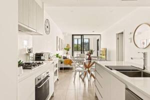 a kitchen with white counters and a table in it at Coastal 2-Bed Apartment near Beach in Deewhy