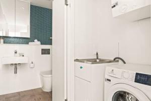 a bathroom with a washing machine and a sink at Coastal 2-Bed Apartment near Beach in Deewhy