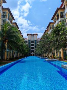 a large swimming pool with palm trees in front of buildings at Desaru Black Beach Sky Mirror Resort in Desaru