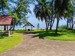 a walkway with palm trees and a gazebo at Desaru Black Beach Sky Mirror Resort in Desaru