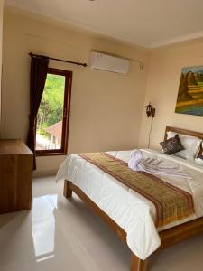 a bedroom with a large bed with a window at Wahadi homestay in Ubud