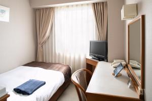 um quarto de hotel com uma cama e uma televisão em Yokote Plaza Hotel em Yokote