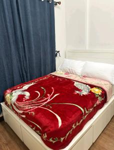 Una cama con una manta roja encima. en Unit N103 Outlook Ridge Residences, en Baguio