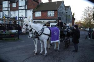 a white horse pulling a carriage down a street at Brambletye Hotel in Forest Row