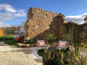 - deux chaises dans un jardin avec un mur en pierre dans l'établissement Holiday home with private pool in Matacães, à Torres Vedras